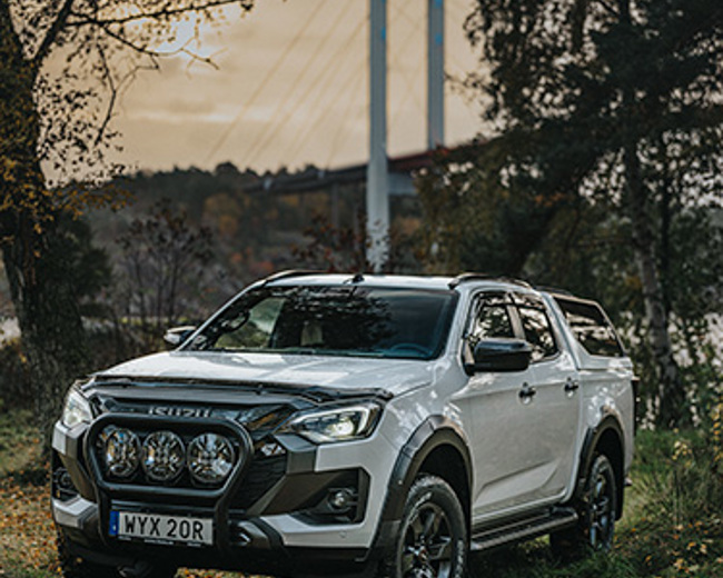 Isuzu D-Max parkerad i skogen nära en bro – redo att ta dig längre, oavsett väg eller väder.