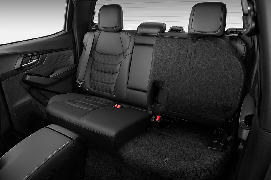 Baksätet i Isuzu D-Max med ena sittdynan uppfälld – visar det praktiska förvaringsutrymmet under sätet.