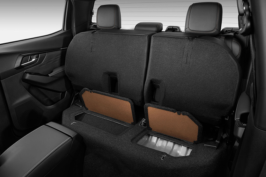 Baksätet i Isuzu D-Max med båda sittdynorna uppfällda – visar det praktiska förvaringsutrymmet under sätet.