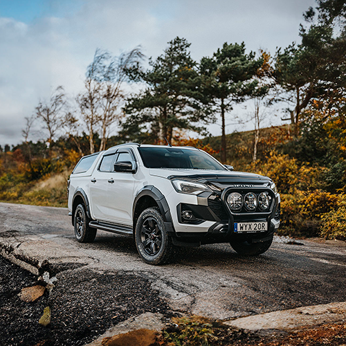 Vit Isuzu D-Max Double Cab med flakkåpa på en ramp i naturskön omgivning – redo för arbete eller äventyr.