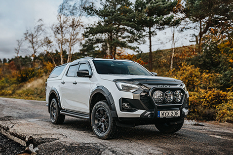 Vit Isuzu D-Max Double Cab med flakkåpa på en ramp i naturskön omgivning – redo för arbete eller äventyr.