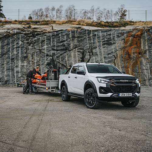 Vit Isuzu D-Max Double Cab med släpvagn kopplad framför en bergvägg – lastad med en 3,5 tons hydraulhammare.