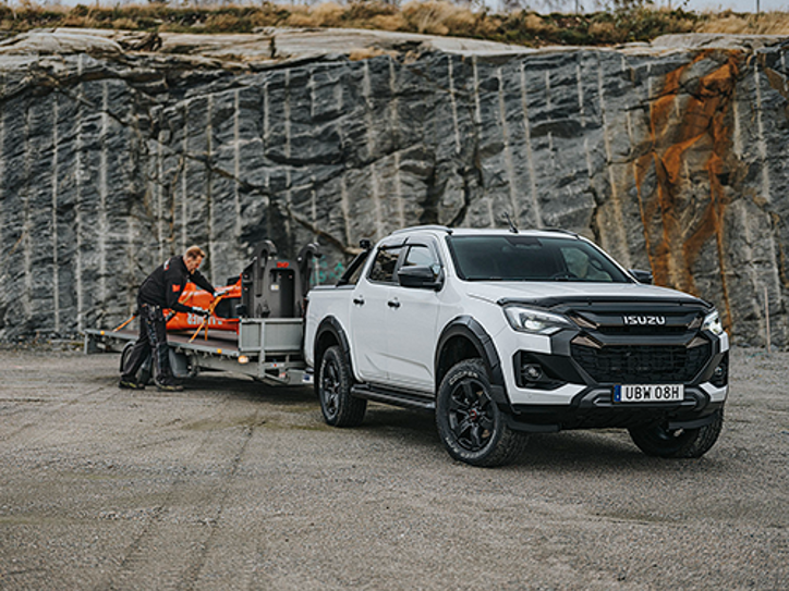 Vit Isuzu D-Max Double Cab med släpvagn kopplad framför en bergvägg – lastad med en 3,5 tons hydraulhammare.