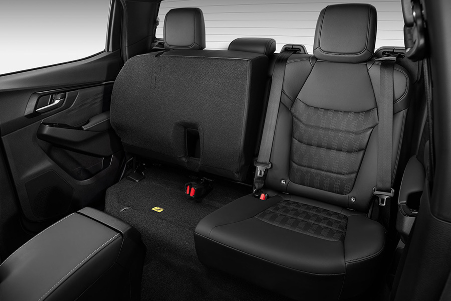 Baksätet i Isuzu D-Max med ena sittdynan uppfälld – visar det praktiska förvaringsutrymmet under sätet.